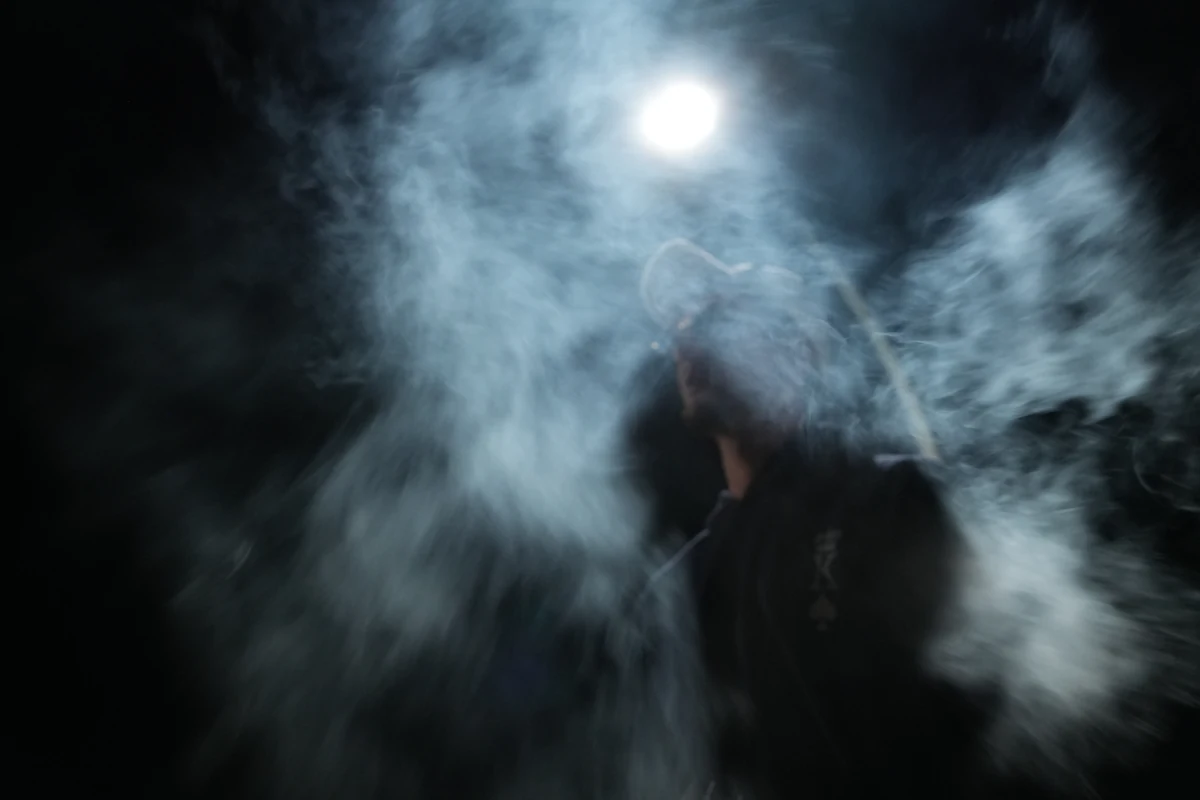 Retrato entre humo y movimiento bajo un foco que brilla como una luna